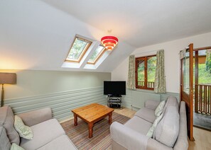 A living room with a sofa set, a coffee table, a TV, and a window with curtains.