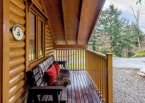 A wooden cabin with a porch, a bench, and a clock on the wall. - 2 bedroom accommodation in Webbery, Bideford (Webbery, Bideford)