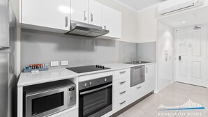 A modern kitchen with white cabinetry, a stainless steel range hood, a built-in oven, and a dishwasher. - One Bedroom in the Heart of  Kangaroo Point with Pool & Parking (Kangaroo Point)