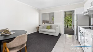 A modern, compact living space with a dining area, a sofa, and a kitchenette. - One Bedroom in the Heart of  Kangaroo Point with Pool & Parking (Kangaroo Point)