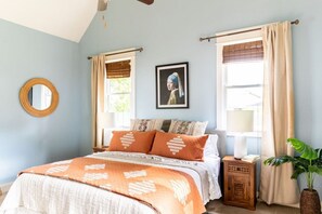 A bedroom with a bed, a round mirror, a framed picture, and a nightstand with a lamp. - Cheerful House near Coffee, Food + Fenced-in Yard (Nashville)