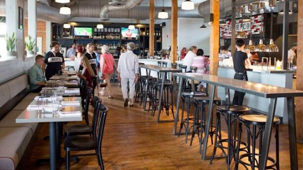A restaurant with high tables and stools, a bar area, and a television screen in the background. - Cheerful House near Coffee, Food + Fenced-in Yard (Nashville)