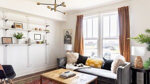 A modern living room with a sofa, coffee table, and shelves. - Cheerful House near Coffee, Food + Fenced-in Yard (Nashville)