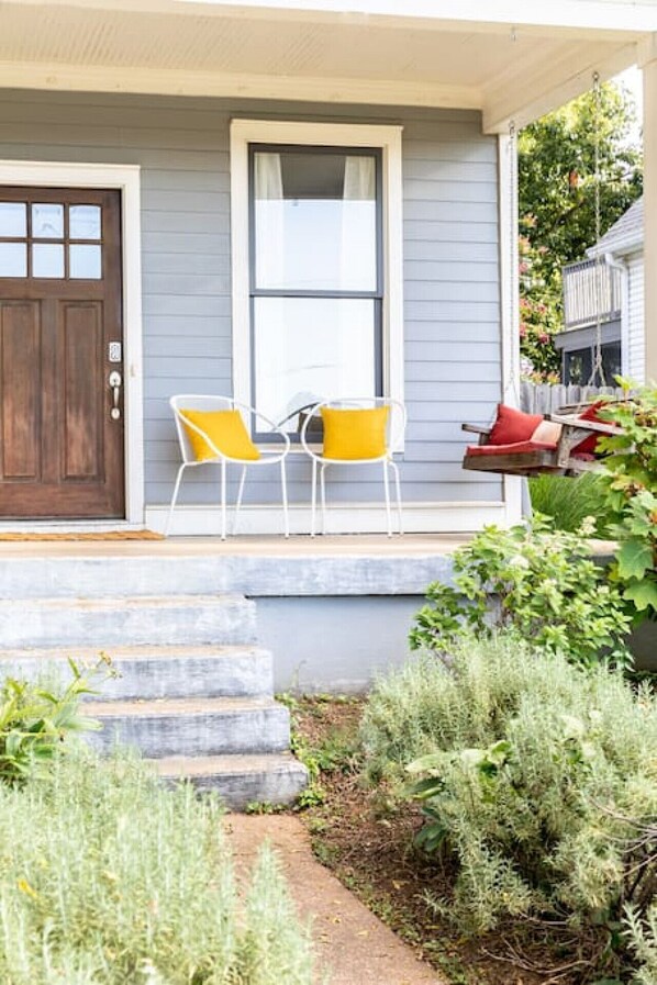 A house with a porch, a brown door, and two yellow chairs.