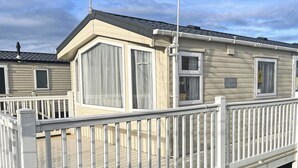Ett husvagn med en veranda, vita räcken och en skylt som visar att det heter ”Cypress”.