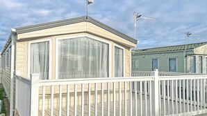 Ett husvagn med en inhägnad veranda, stora fönster och en satellitmottagare.