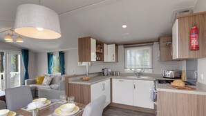 A modern kitchen with a dining area, wooden cabinets, and a fire extinguisher.