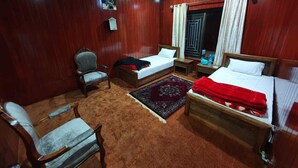 Een hotelkamer met twee eenpersoonsbedden, een houten stoel, een klein tafeltje en een vloerbedekking.