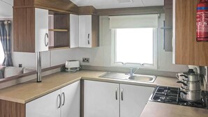 A compact kitchen with a sink, stove, and storage cabinets.