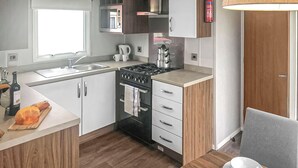 A modern kitchen with a stove, sink, and wooden cabinets.