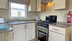 A compact kitchen with a sink, stove, oven, and a window.