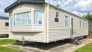 A mobile home with a flat roof, a chimney, and a satellite dish.