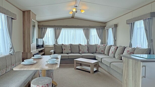 A spacious living area with a sofa, a dining table, and a kitchen counter.