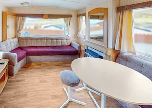Un intérieur de camping-car compact comprenant un canapé, une table à manger et un petit tabouret.
