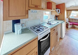Une cuisine de taille réduite équipée d’une cuisinière à gaz, d’un évier et d’un four à micro-ondes.