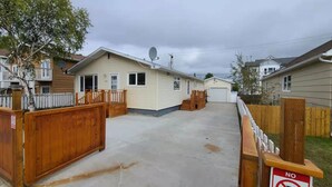 A residential area with single-story houses, a concrete driveway, and wooden fences. -  YK Aurora B&B  (Yellowknife)