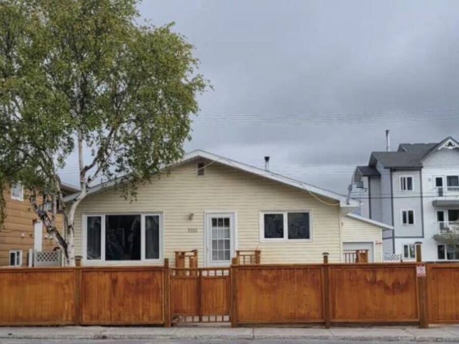 A row of single-story houses with a wooden fence in the foreground.