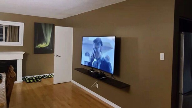A living room with a flat-screen TV mounted on the wall, a fireplace, and a dining area with chairs and a table. -  YK Aurora B&B  (Yellowknife)