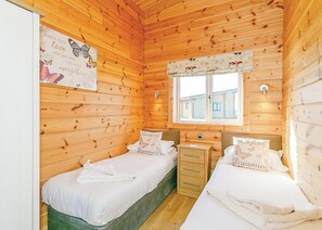 Una habitación de cabaña de madera con dos camas, un ventanal y un cartel en la pared.