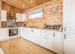 Una cocina moderna con paredes de madera, una campana extractora de acero inoxidable, un horno empotrado y una ventana con cortina.