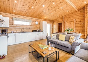 Interior de una cabaña de madera con cocina, comedor y sala de estar.