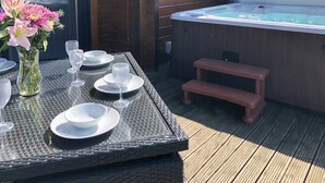 Ruokapöytä katettuna, ja sen yhteydessä poreallas sekä puinen terassi.