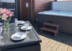 Une table dressée pour le dîner, avec un jacuzzi et une terrasse en bois.