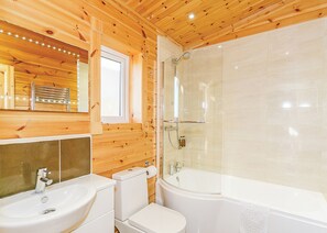 A wooden cabin bathroom with a sink, toilet, and bathtub.
