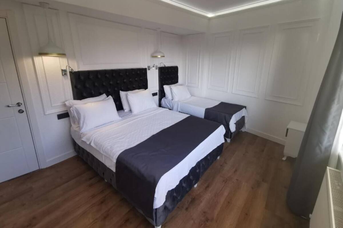 A bedroom with two beds, white walls, and a wooden floor.