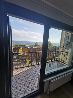 A balcony with patterned floor tiles, a metal railing, and a view of the sea with ships in the distance. - HOTEL EFZEN (Istanbul)