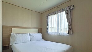 Une chambre d’hôtel avec un grand lit, une tête de lit, une fenêtre avec des rideaux et une vue sur les bâtiments environnants.