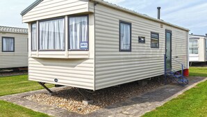 Une maison mobile dotée d’une porte d’entrée, de fenêtres et d’une cheminée.