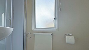 A bathroom with a toilet, a sink, a window, and a towel rack. - Comfortable caravan with one double and one twin. (Mablethorpe, Skegness)