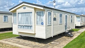 A mobile home with a covered porch, a satellite dish, and a small outdoor area with steps. - Comfortable caravan with one double and one twin. (Mablethorpe, Skegness)