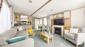 En moderne stue med sofa, lænestole, sofabord, pejs og fjernsyn.