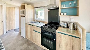 Une cuisine de taille réduite équipée d’une cuisinière, d’un four, d’un four à micro-ondes et d’une fenêtre.