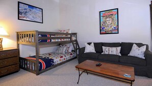 A bunk bed with a colorful bedspread, a sofa with patterned cushions, and a coffee table with a remote control. - First Tracks CB, Slopeside, true ski in/out above kids ski school! (Crested Butte)