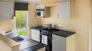 A compact kitchen with a gas stove, oven, microwave, and a sink.