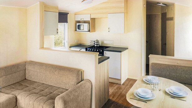 A compact living space with a kitchenette, a sofa, a dining table, and a small kitchen area.