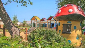 A mushroom-shaped playhouse with a small window, surrounded by greenery and other colorful play structures. - 2 bedroom accommodation in Gwespyr, Nr Prestatyn, Denbighshire (Gwespyr, Nr Prestatyn, Denbighshire)