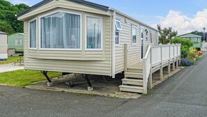 A mobile home with a large window, a porch, and a small staircase leading up to the entrance. - 2 bedroom accommodation in Gwespyr, Nr Prestatyn, Denbighshire (Gwespyr, Nr Prestatyn, Denbighshire)