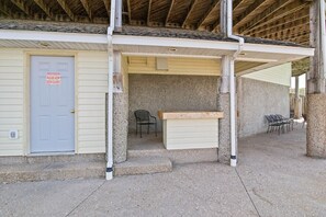 A building with a closed door marked "Please Keep Door Closed," a concrete bench, and outdoor seating. - Ledges Landing – Waterfront Condo, Beach, & Pools! (Osage Beach)