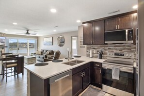 A modern kitchen with dark wood cabinets, stainless steel appliances, and a large island with a sink.
