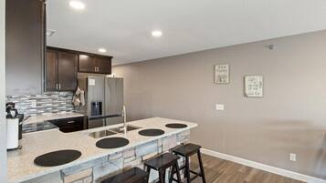 A modern kitchen with a central island, bar stools, and a refrigerator.