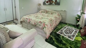Une chambre à coucher avec un lit, un canapé, une petite table et un tapis vert.