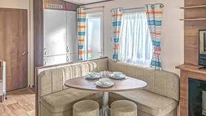 Una kitchenette con refrigerador, una mesa de comedor con sillas y un sofá.