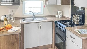 Una cocina compacta con microondas, fregadero, estufa y armarios.