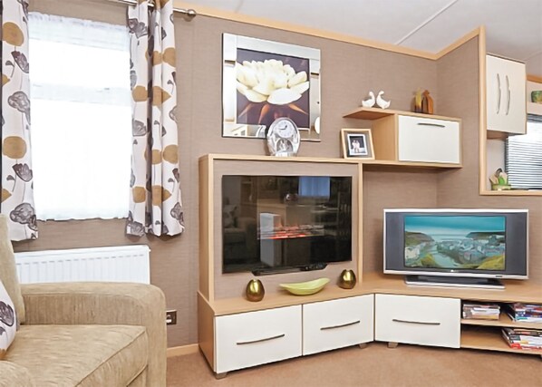 A living room with a TV, a sofa, a cabinet, and a window with curtains.