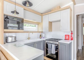 Una cocina moderna con horno empotrado, microondas y cocina a gas.