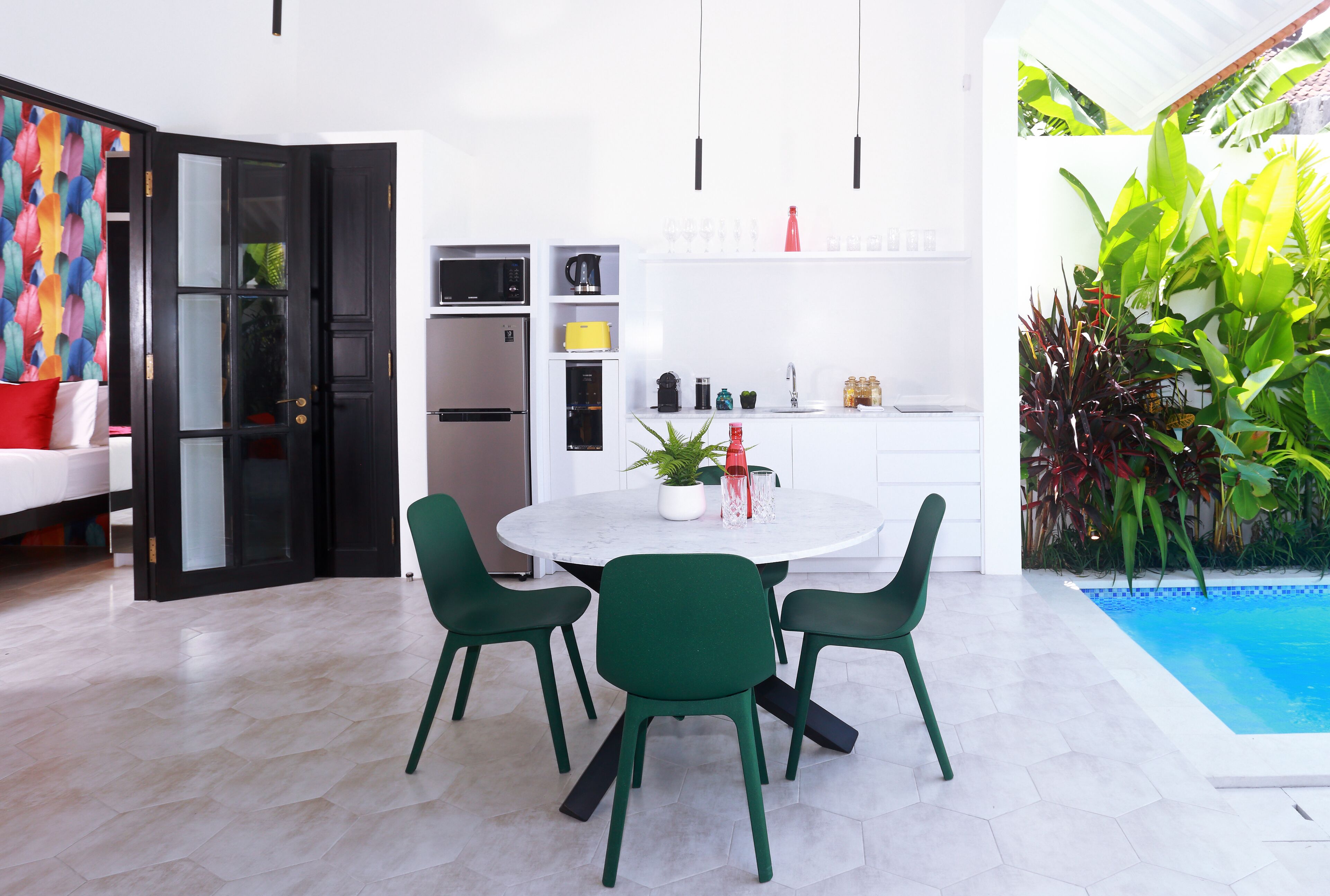 Une cuisine moderne avec un plan de travail blanc, des chaises vertes et une table à manger.